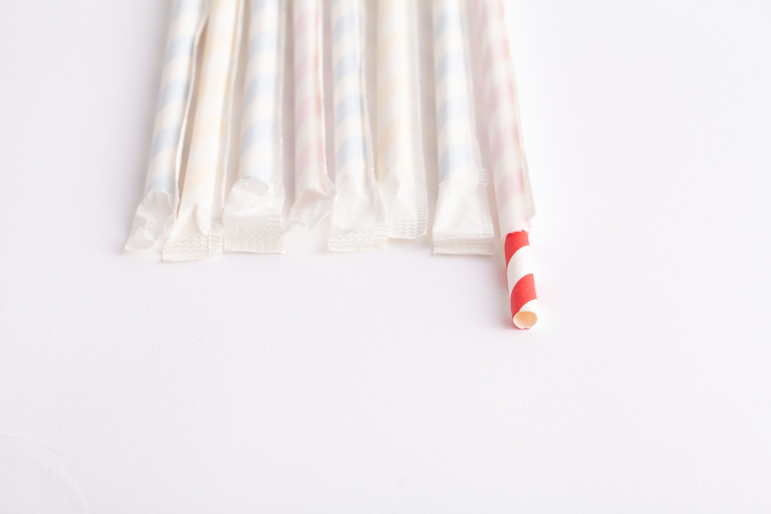 paper straws lined up side by side, 1 straw is open
